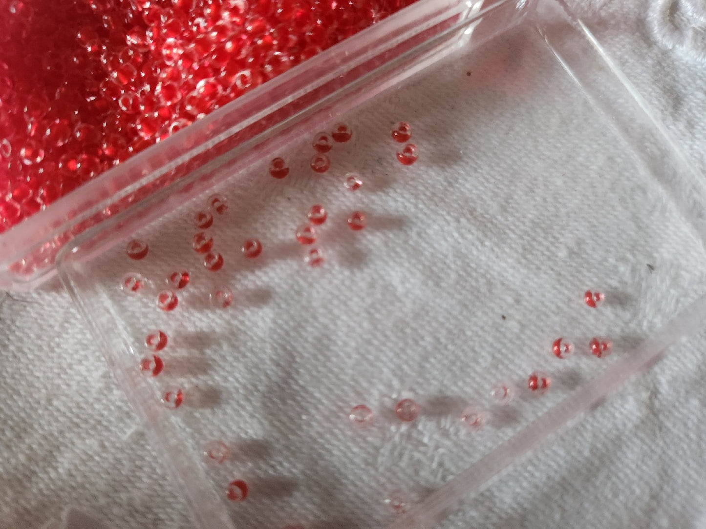 Lot environ 22 grammes de perles rocaille deux tons rouge et transparente  n°26