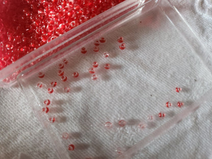 Lot environ 22 grammes de perles rocaille deux tons rouge et transparente  n°26